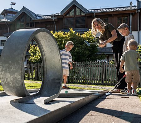Frau und Kinder spielen gemeinsam Minigolf auf der Minigolfanlage in Flachau.