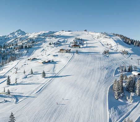 Eine Drohnenaufnahme vom Skigebiet Snow Space Salzburg in Flachau mit Pisten, Bergen und Liften.