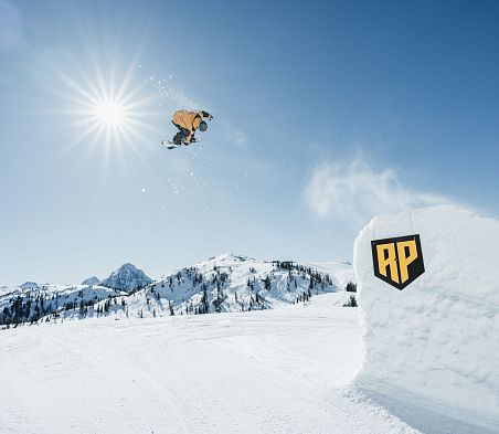 Freestyler zeigt einen Trick auf einer Kicker im Absolut Park Flachawinkl in schöner Winterlandschaft.