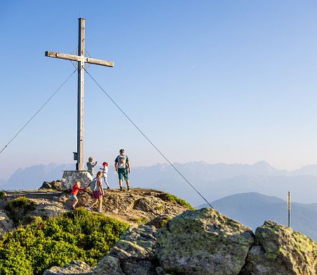 Familie erreicht einen Gipfel mit Gipfelkreuz in Flachau und genießt das Panorama der Salzburger Alpen.