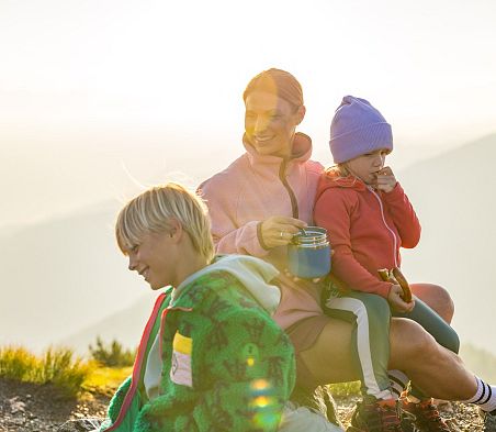Mutter und Kinder machen eine Pause beim Wandern in Flachau und genießen den Familienurlaub in den Bergen.