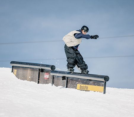 Freestylerin auf einer Rail im Absolut Park am Shuttleberg Flachauwinkl-Kleinarl vor blauem Himmel.