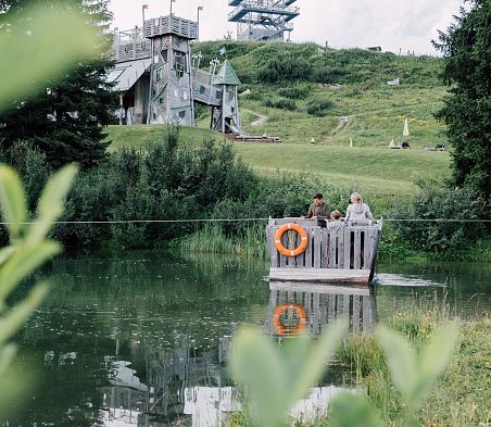 Familie fährt auf Floß über Geistersee mit Geisterschloss im Hintergrund
