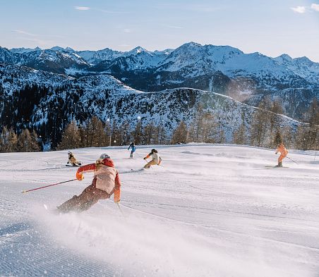 Skifahrer genießen frische Piste mit genialem Alpenpanorama im Skiparadies Zauchensee.