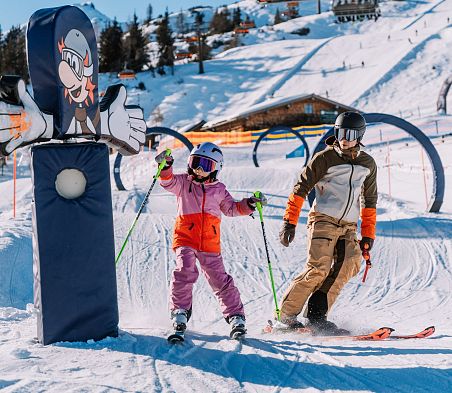 Kind und Erwachsener fahren Ski und haben Spaß am Kidsparcours im Snow Space Salzburg