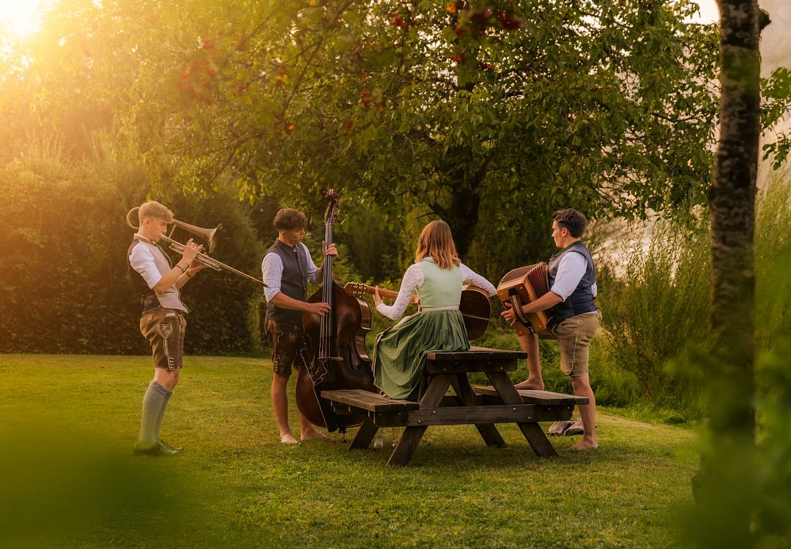 Eine Gruppe von jungen Männern und Frauen gemeinsam beim Musizieren und Feiern im Bauernherbst im Salzburger Land.