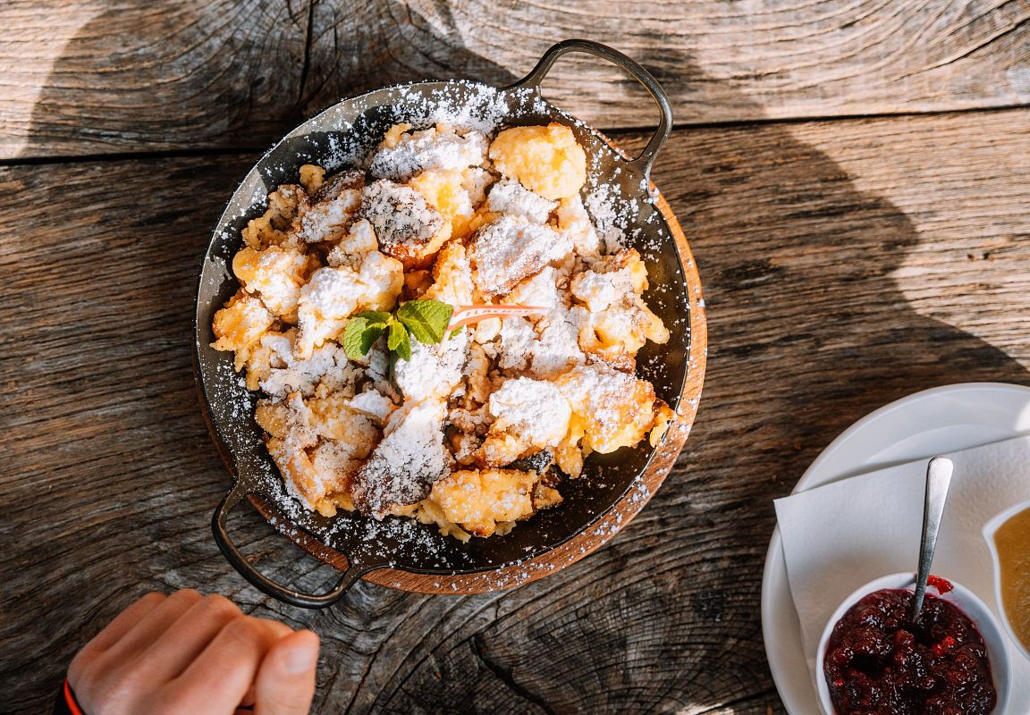 Kaiserschmarrn mit Puderzucker auf Holztisch auf einer Huette in Flachau, Spezialität im Salzburger Land.