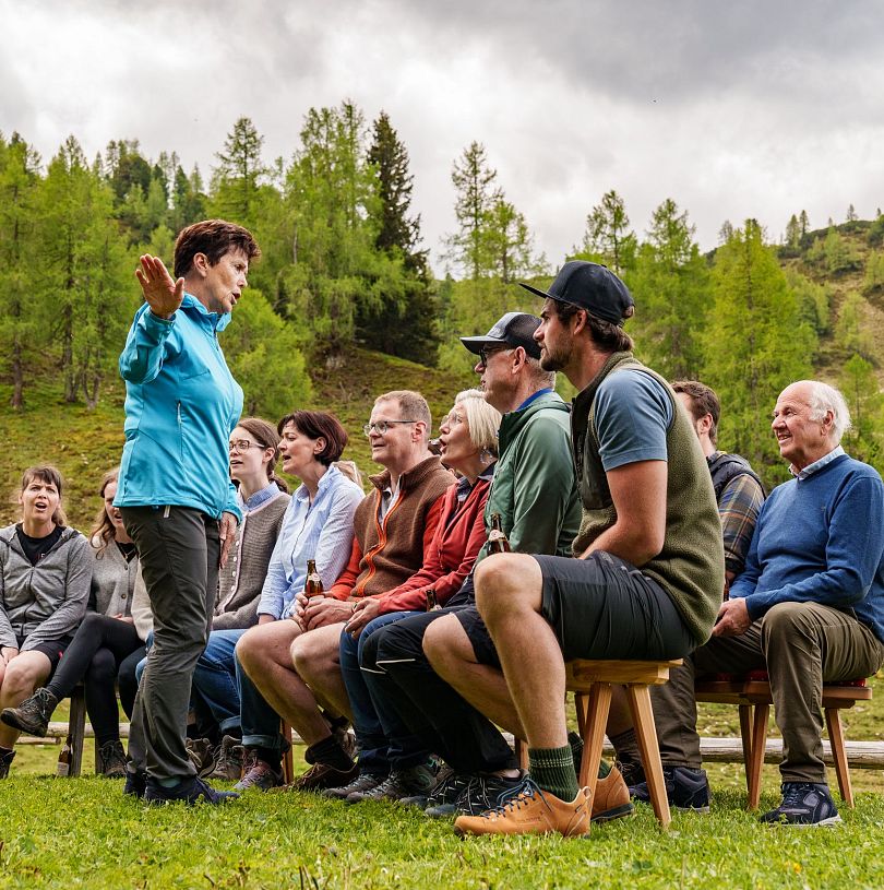 Eine Dame mit blauer Jacke leitet einen Chor bei einer musikalischen Wanderung in Flachau.