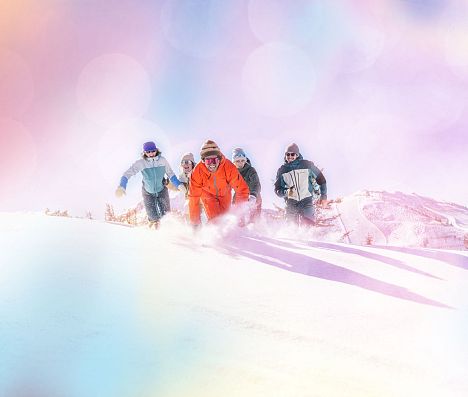 Fünf Personen laufen durch Tiefschnee in Flachau. Das Bild hat einen bunten Filter.