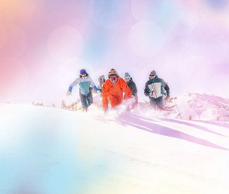 Fünf Personen laufen durch Tiefschnee in Flachau. Das Bild hat einen bunten Filter.
