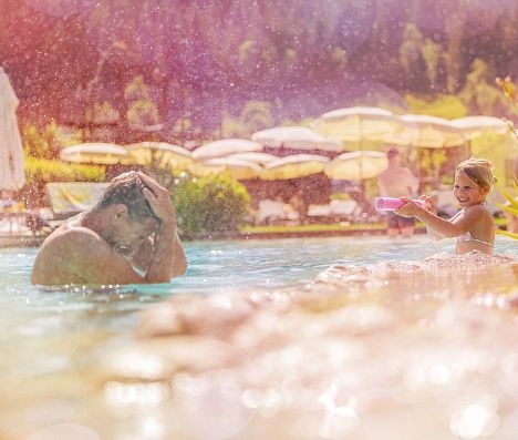 Vater und Kind spielen im Wasser in enem Pool in Flachau, Salzburgerland.