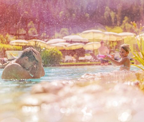 Vater und Kind spielen im Wasser in enem Pool in Flachau, Salzburgerland.