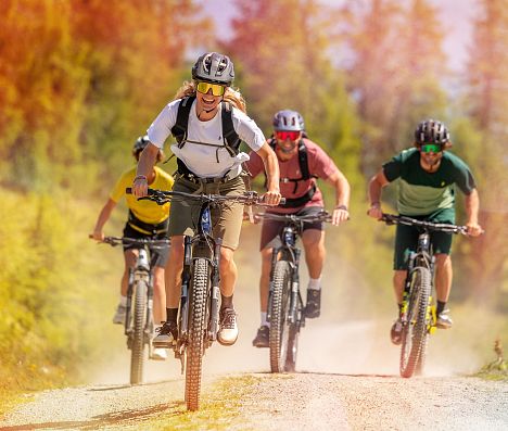 Vier Mountainbiker fahren auf einer Schotterstraße in Flachau, Salzburgerland den Berg hinauf.