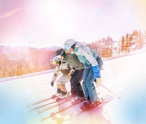 Drei Skifahrer fahren gemeinsam auf einer Piste in Flachau und halten sich aneinander fest. Das Bild hat einen bunten Filter.