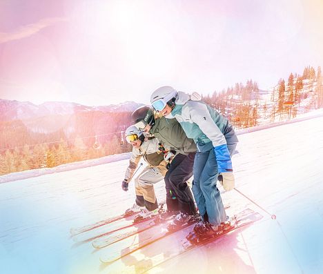 Drei Skifahrer fahren gemeinsam auf einer Piste in Flachau und halten sich aneinander fest. Das Bild hat einen bunten Filter.