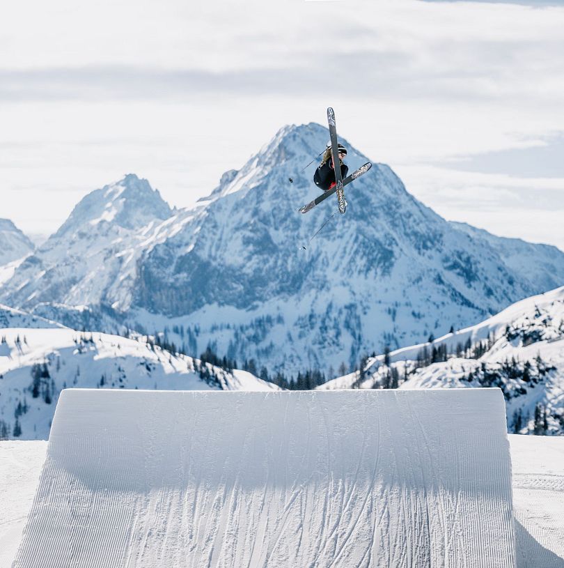 Skifahrer in der Luft zeigt einen Trick vor einer schönen Winterlandschaft.