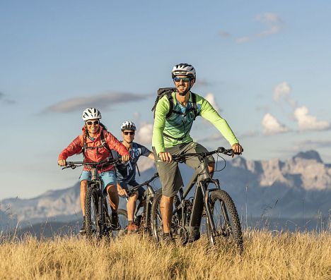 Mountainbiker fahren über ein Almgebiet mit weitem Blick auf die imposanten Berge m Salzburger Land.