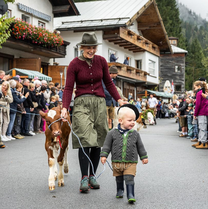 Frau und Kind führen ein Kalb beim traditionellen Umzug in Flachau, Salzburger Land