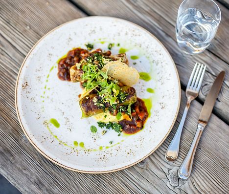 Angerichtetes Hauptgericht mit regionalen Zutaten auf einem Teller auf einem Holztisch in Flachau.