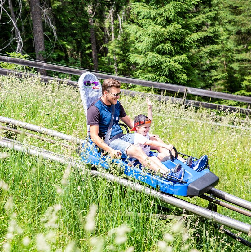 Vater und kleiner Sohn haben gemeinsam Spaß am Alpine Coaster Lucky Flitzer in Flachau.
