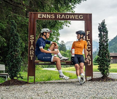 Radfahrerinnen pausieren am Startpunkt des Ennsradwegs in Flachau, Salzburger Land
