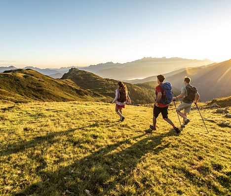 Drei Wanderer beim Abstieg im goldenen Abendlicht.