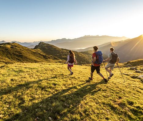 Drei Wanderer beim Abstieg im goldenen Abendlicht.