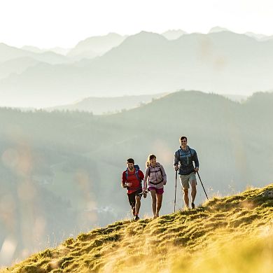 Wanderer erklimmen einen Bergrücken in Flachau, im Hintergrund erkennt man das beeindruckende Panorama.