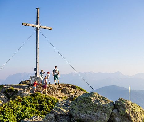 Familie erreicht einen Gipfel mit Gipfelkreuz in Flachau und genießt das Panorama der Salzburger Alpen.