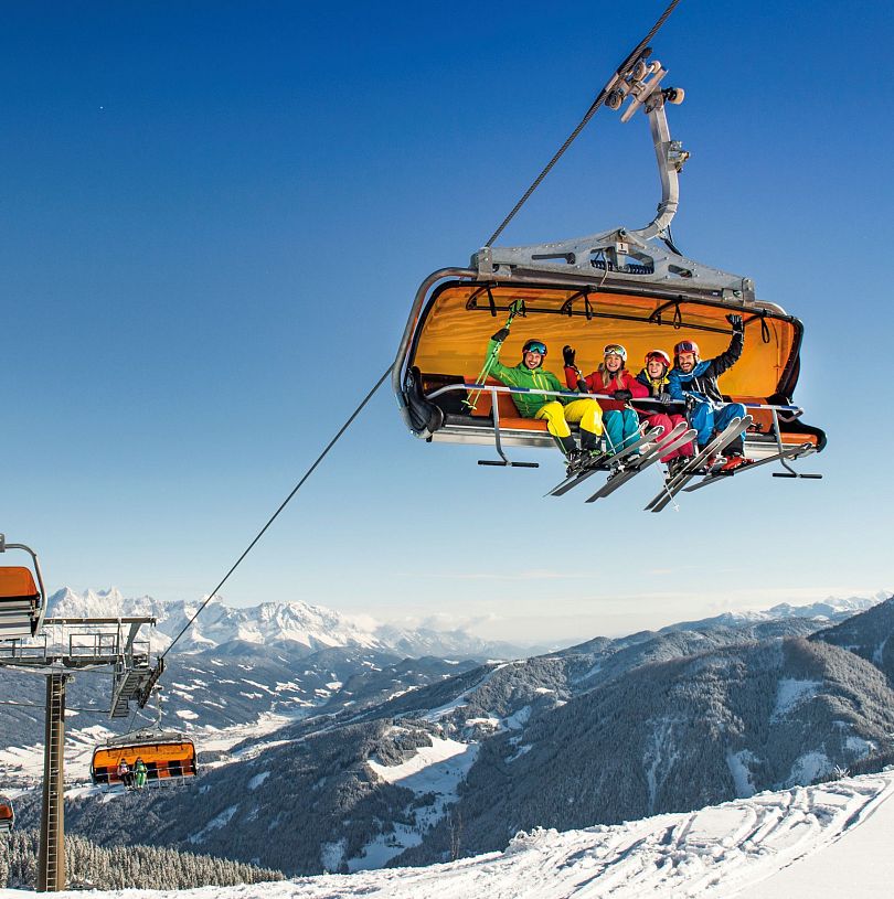Skifahrer im Sessellift mit Panoramablick auf die Alpen in Flachau, Ski amadé, Salzburger Land.