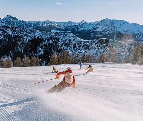 Skifahrer genießen frische Piste mit genialem Alpenpanorama im Skiparadies Zauchensee.