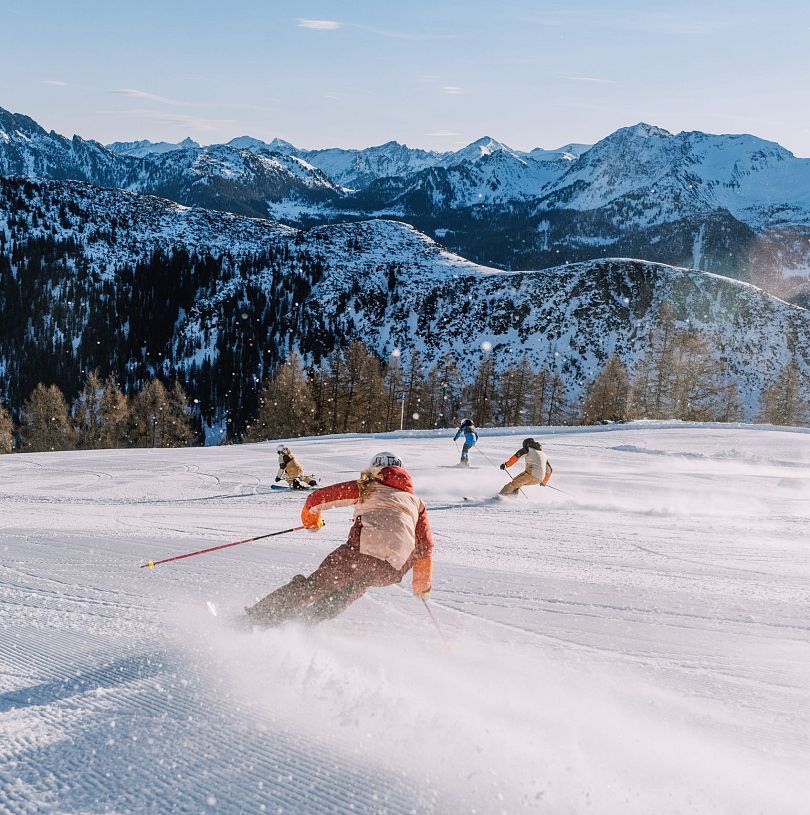 Skifahrer genießen frische Piste mit genialem Alpenpanorama im Skiparadies Zauchensee.