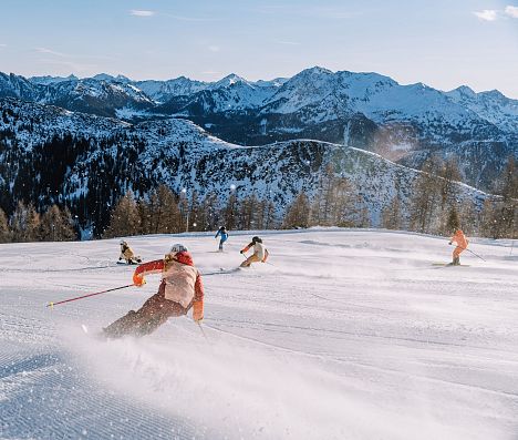 Skifahrer genießen frische Piste mit genialem Alpenpanorama im Skiparadies Zauchensee.