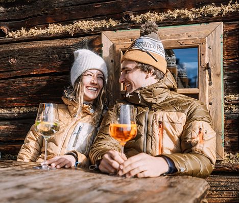 Paar genießt Getränke in der Wintersonne vor einer Hütte  in Flachau, Ski amadé.