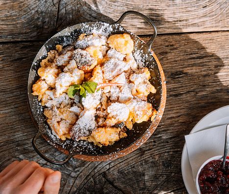 Kaiserschmarrn mit Puderzucker auf Holztisch auf einer Huette in Flachau, Spezialität im Salzburger Land.