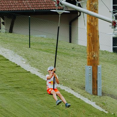 Junge gleitet mit der Fly-Line auf einem Tellersitz über den Hang in Flachau.