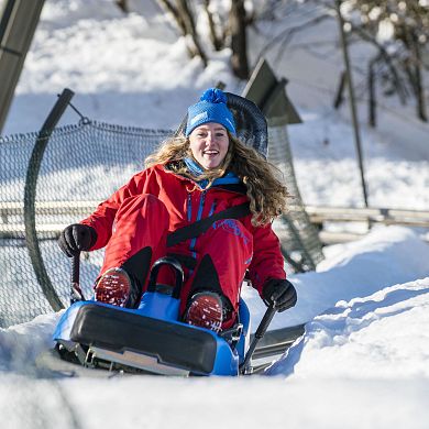 Junge Frau hat Spaß bei ihrer Fahrt mit dem Alpincoaster Lucky Flitzer in Flachau.