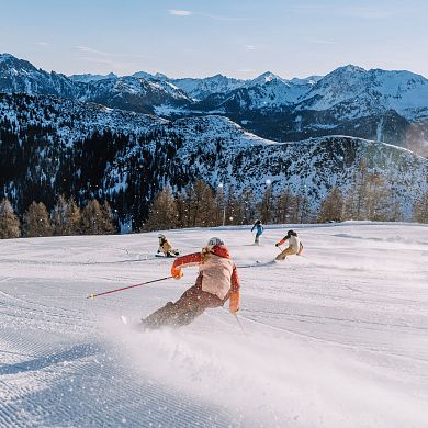 Skifahrer genießen frische Piste mit genialem Alpenpanorama im Skiparadies Zauchensee.